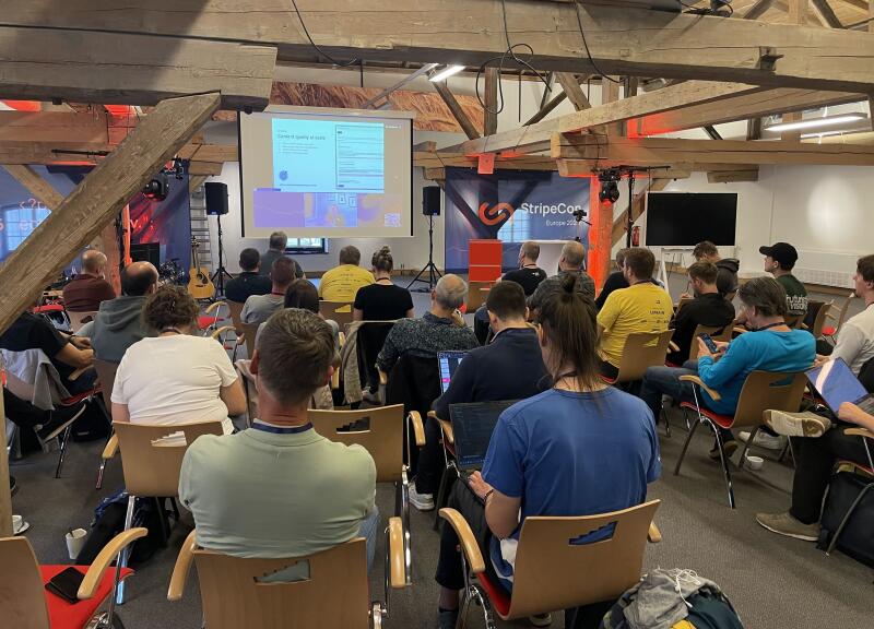 Attendees at StripeCon 2026, listening to an online speaker